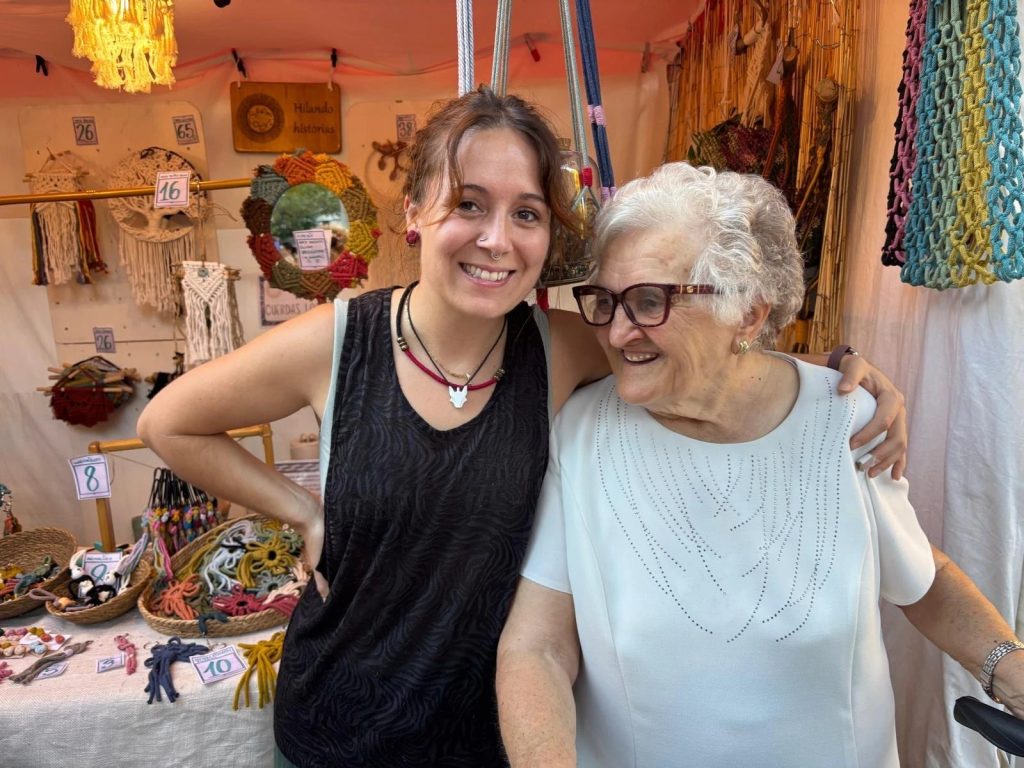 Inés Castán abraza a su abuela en su puesto de macramé Cuerdas Locas, en la plaza de los Sitios de Zaragoza